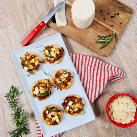 Photo de tartelettes d'échalotes confites et charolais AOP posées sur une assiette en céramique et un torchon rouge et blanc.
